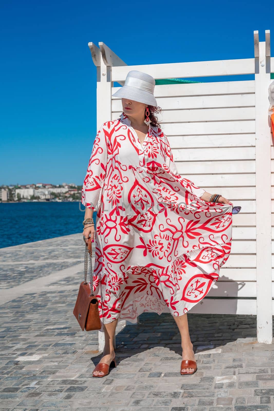 woman in a hat and dress enjoys the blue sea and summer. Welcome summer