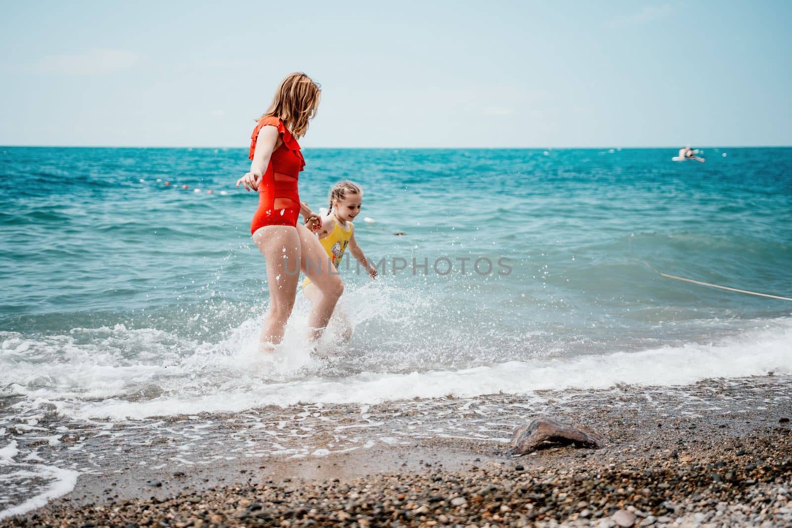 Happy loving family mother and daughter having fun together on the beach. Mum playing with her kid in holiday vacation next to the ocean - Family lifestyle and love concept by panophotograph