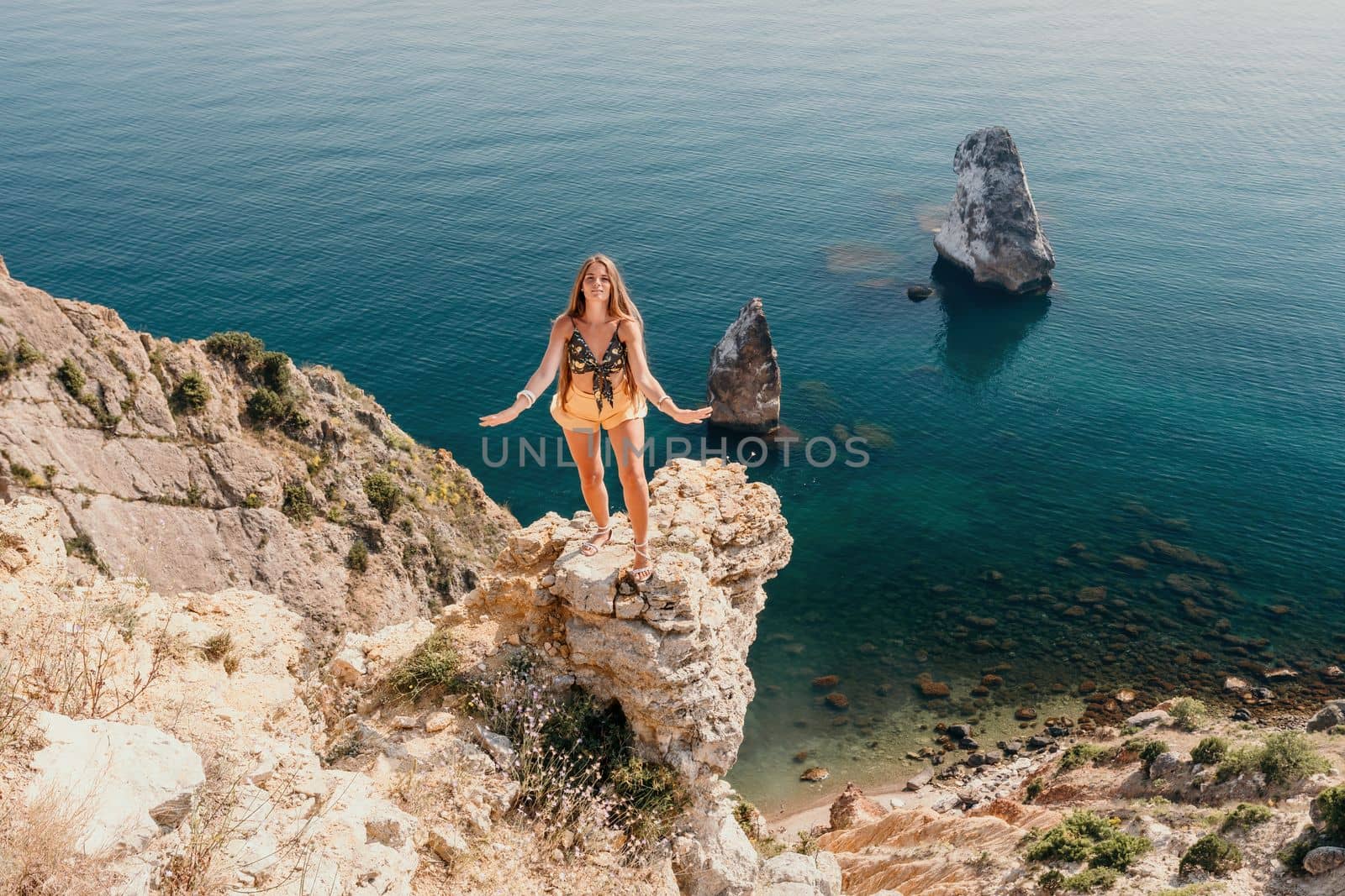 Woman travel sea. Happy tourist enjoy taking picture outdoors for memories. Woman traveler looks at the edge of the cliff on the sea bay of mountains, sharing travel adventure journey by panophotograph