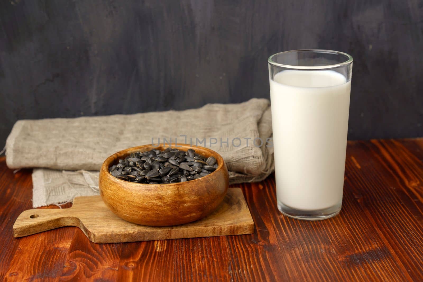 Sunflower milk in a glass, raw seeds,wooden background. Dairy free alternative