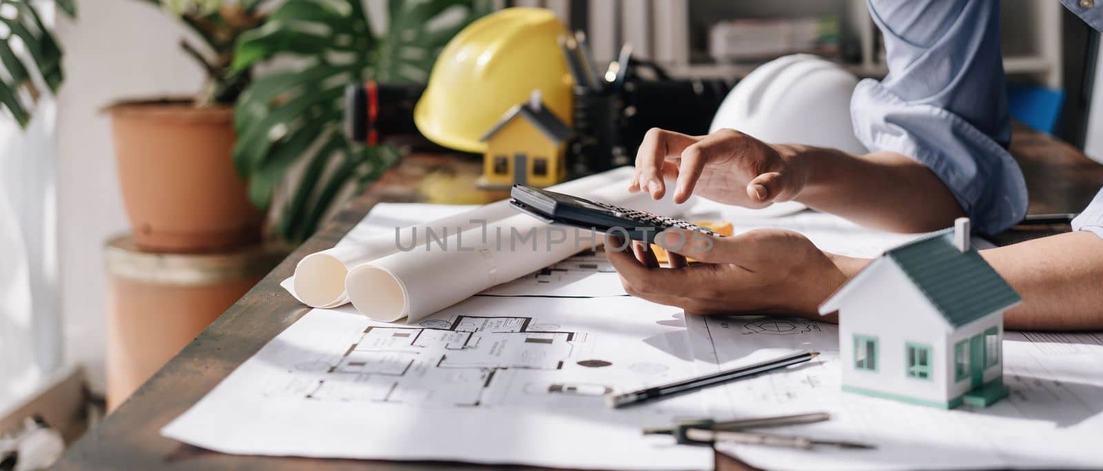 Image of engineer drawing a blue print design building or house, An engineer workplace with blueprints, pencil, protractor and safety helmet, Industry concept..