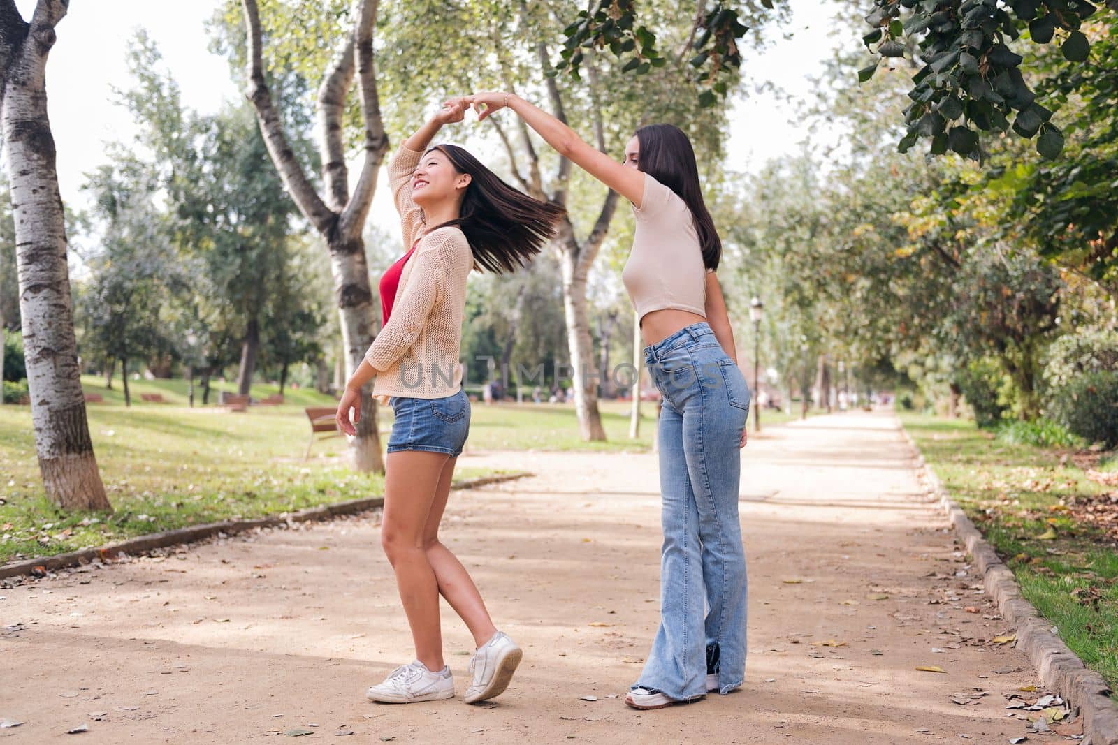 couple of happy women dancing and having fun during a date in a park, concept of friendship and love between people of the same sex