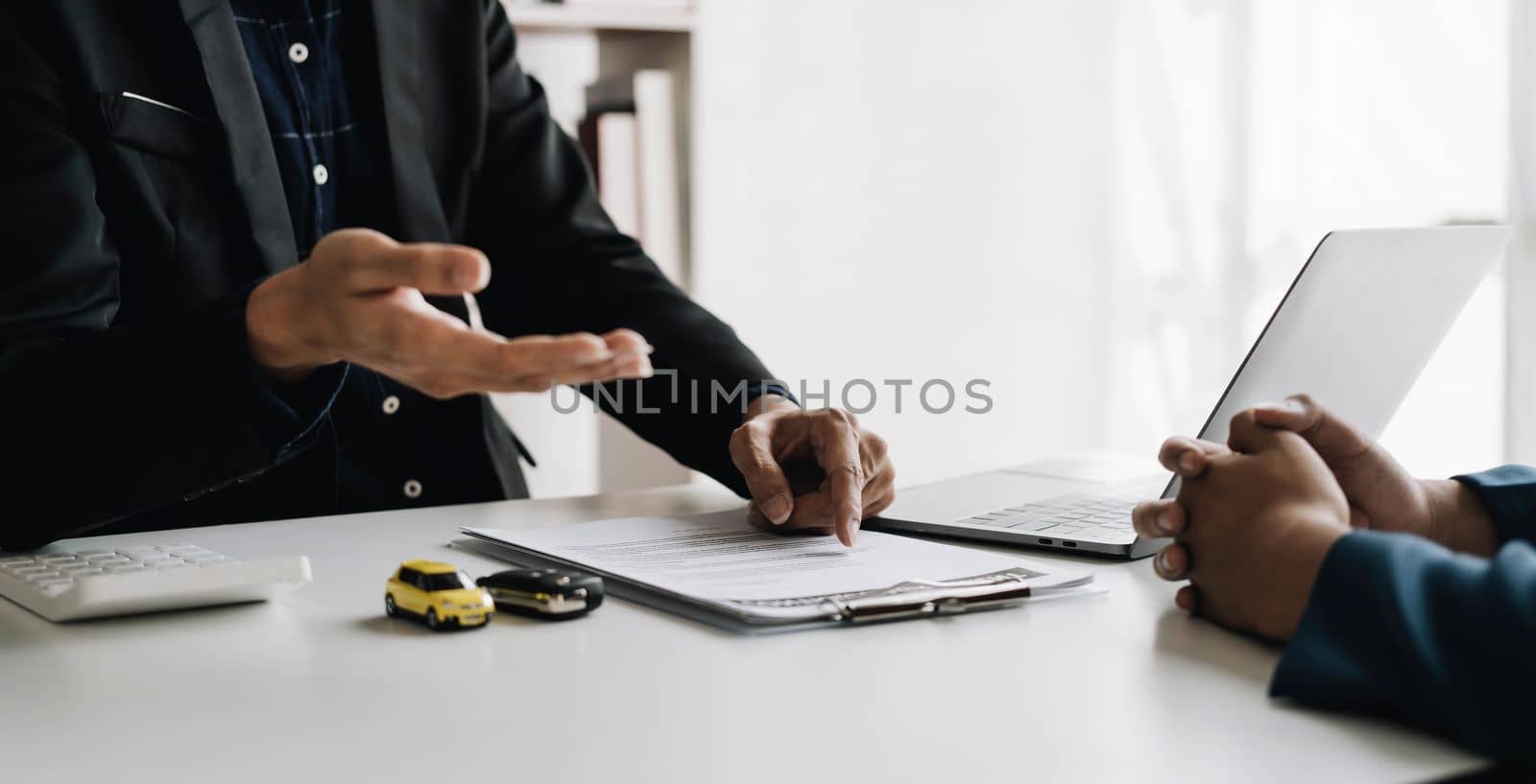 Car agent, sale man explain terms and agreement to customer before giving the car key to customer. by wichayada