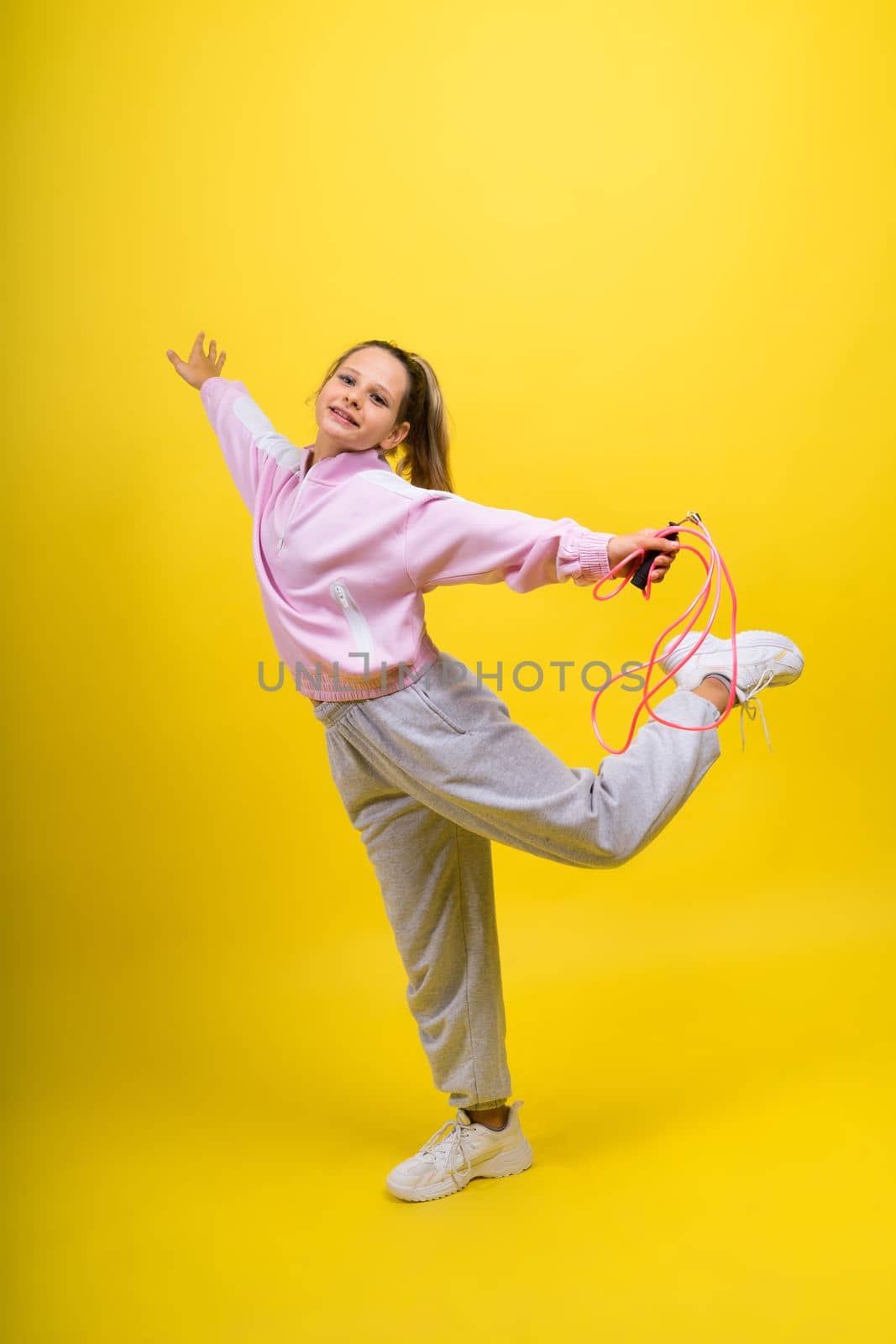 Adorable female child with skipping rope jumping in studio by Zelenin