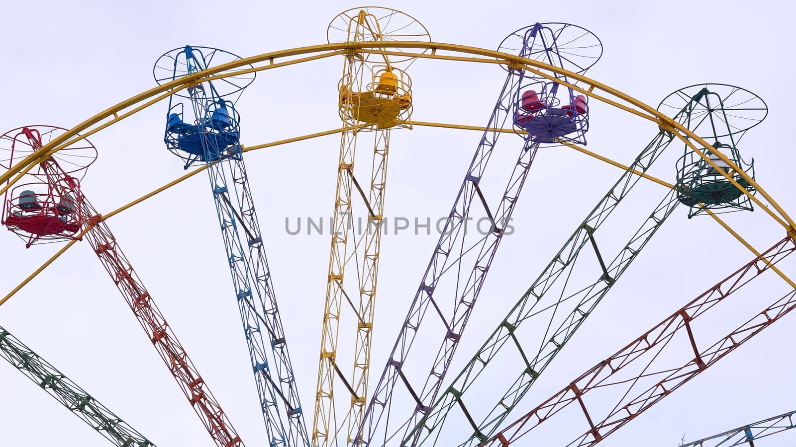 an amusement park or fairground ride consisting of a giant vertical revolving wheel with passenger cars suspended on its outer edge.