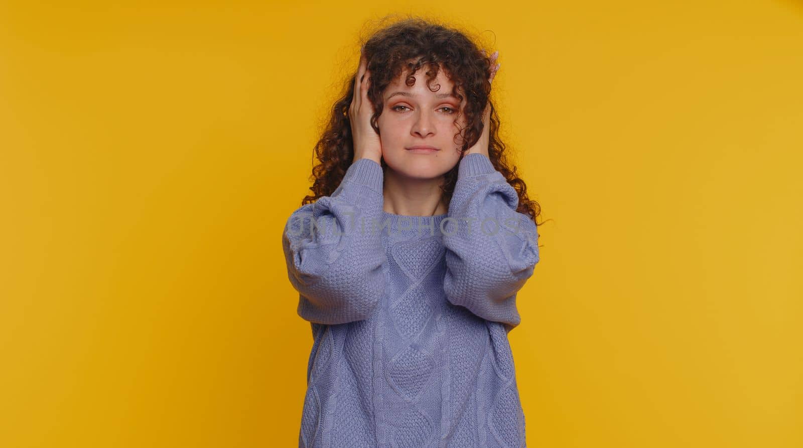 Dont want to hear and listen. Frustrated annoyed irritated curly haired woman covering ears gesturing No, avoiding advice ignoring unpleasant noise loud voices. Young girl on studio yellow background