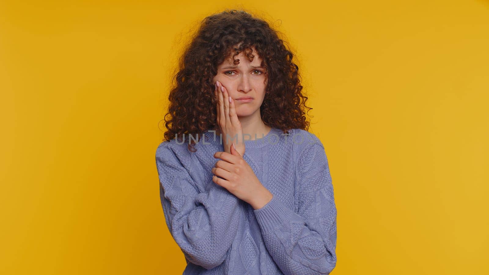 Woman touching cheek suffering from toothache cavities or gingivitis waiting for dentist appointment by efuror