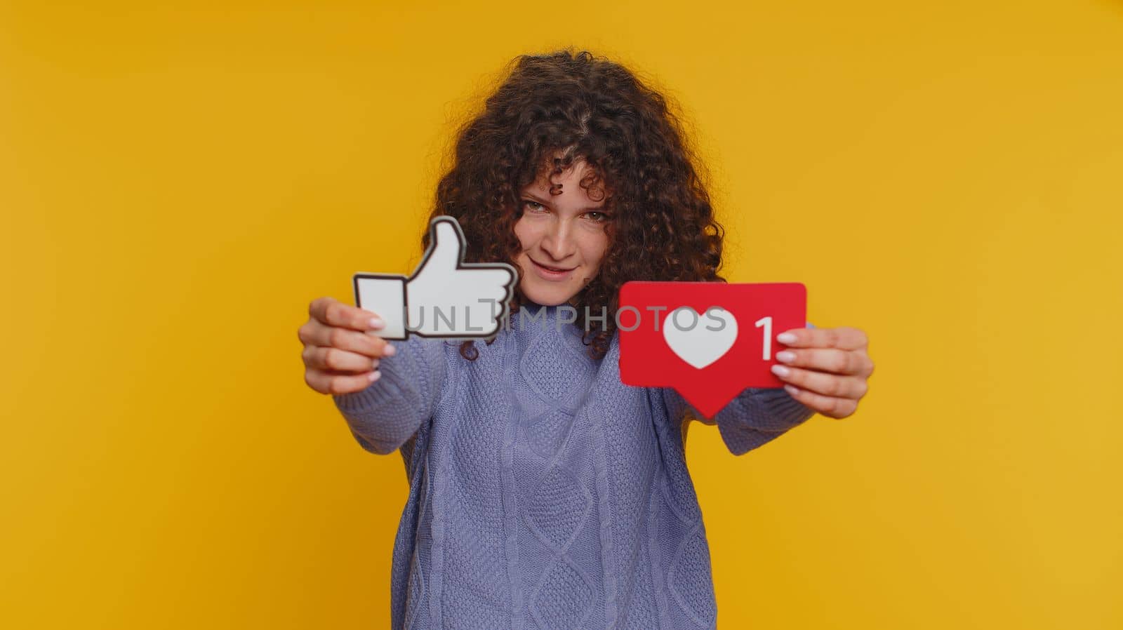 Like. Curly haired woman raises inscription thumbs up banner thumbs up agrees with something, gives positive reply recommends advertisement likes good on social media. Young girl on yellow background