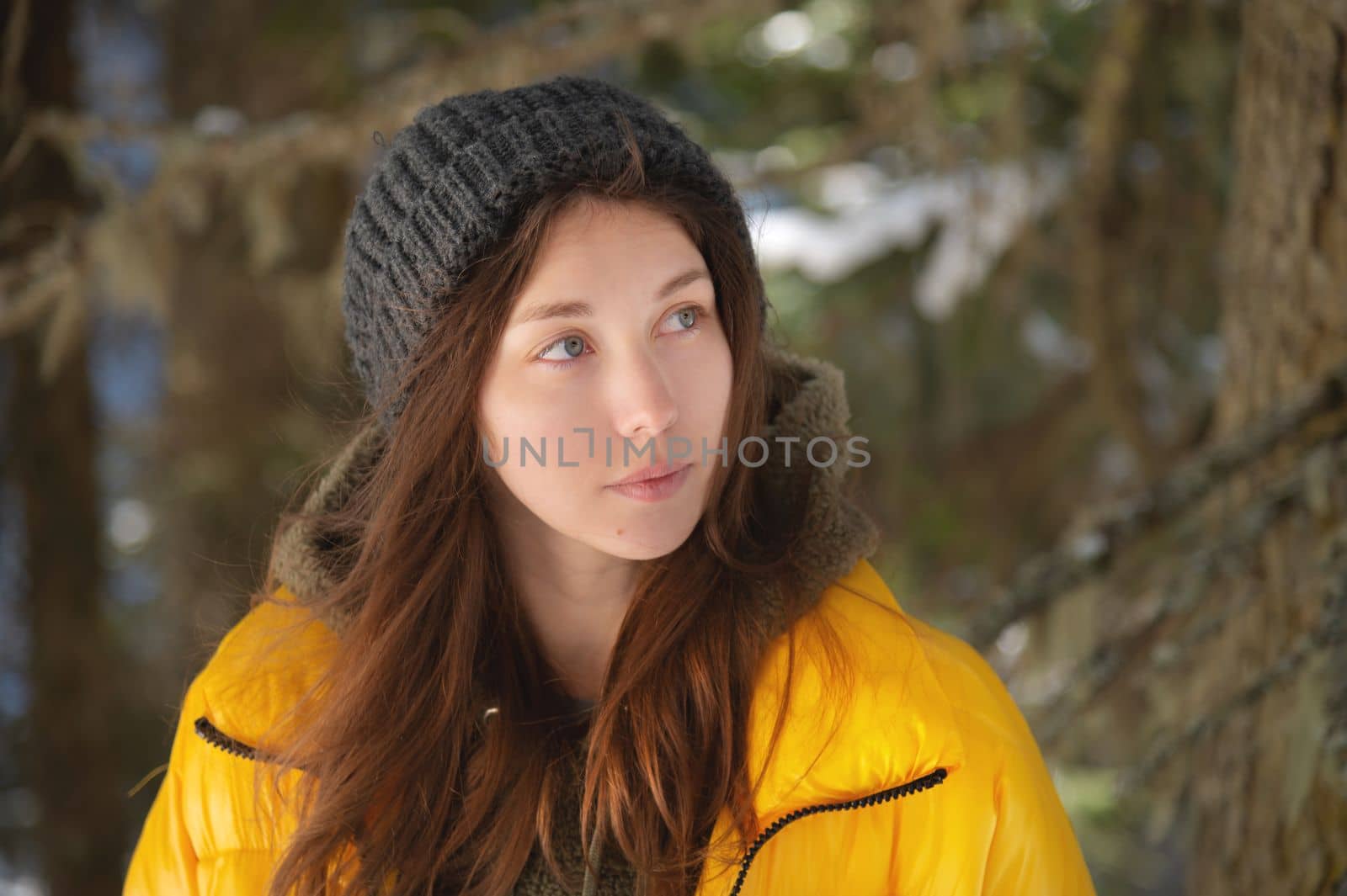 Enjoy winter outdoors. Portrait of young hipster girl happy laughing during walk in snowy pine forest, park or woods outside city. Joyful woman in warm hat and trendy coat enjoy frost and snow.