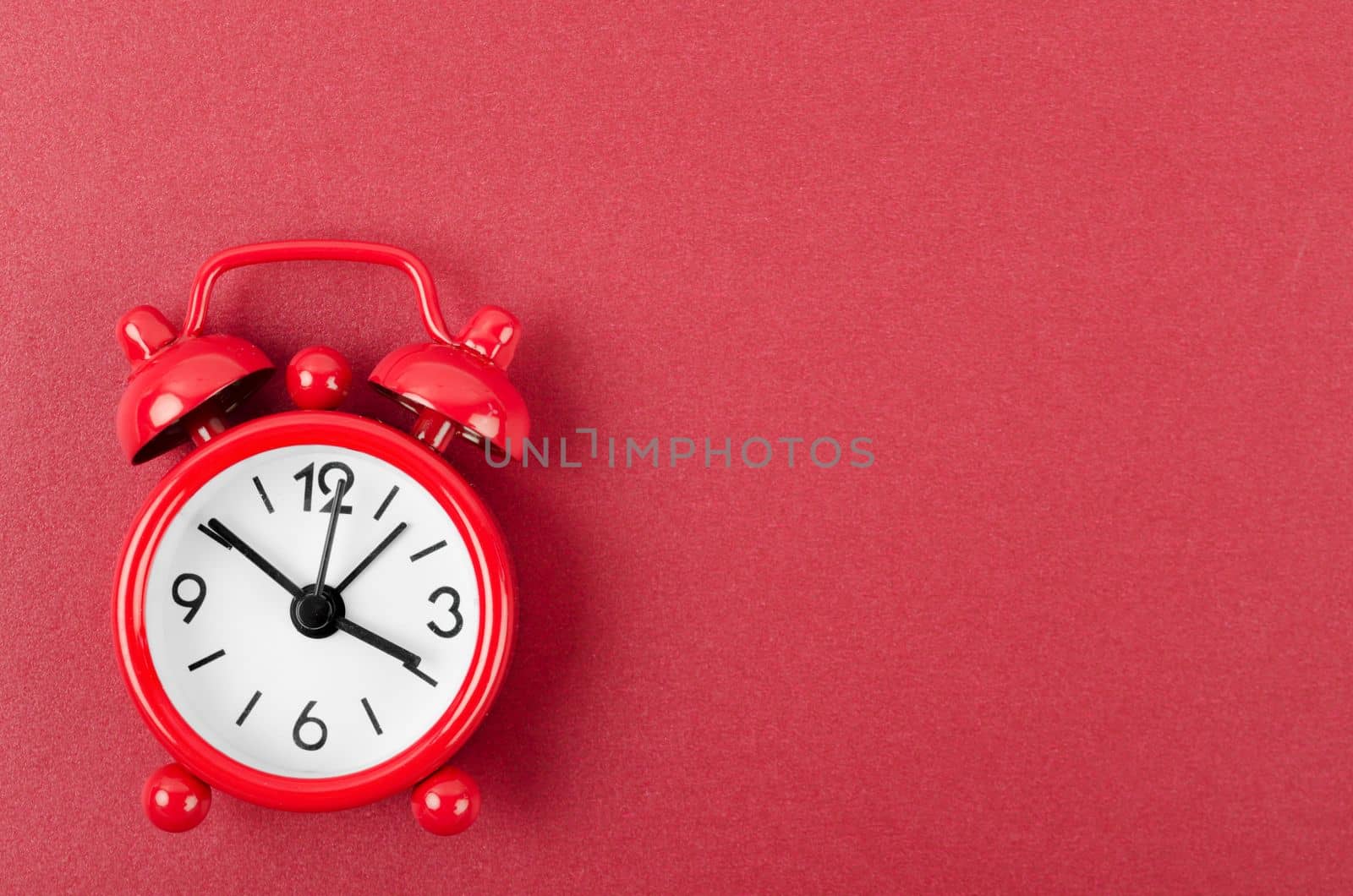 The Red alarm clock on red colour background. by Gamjai