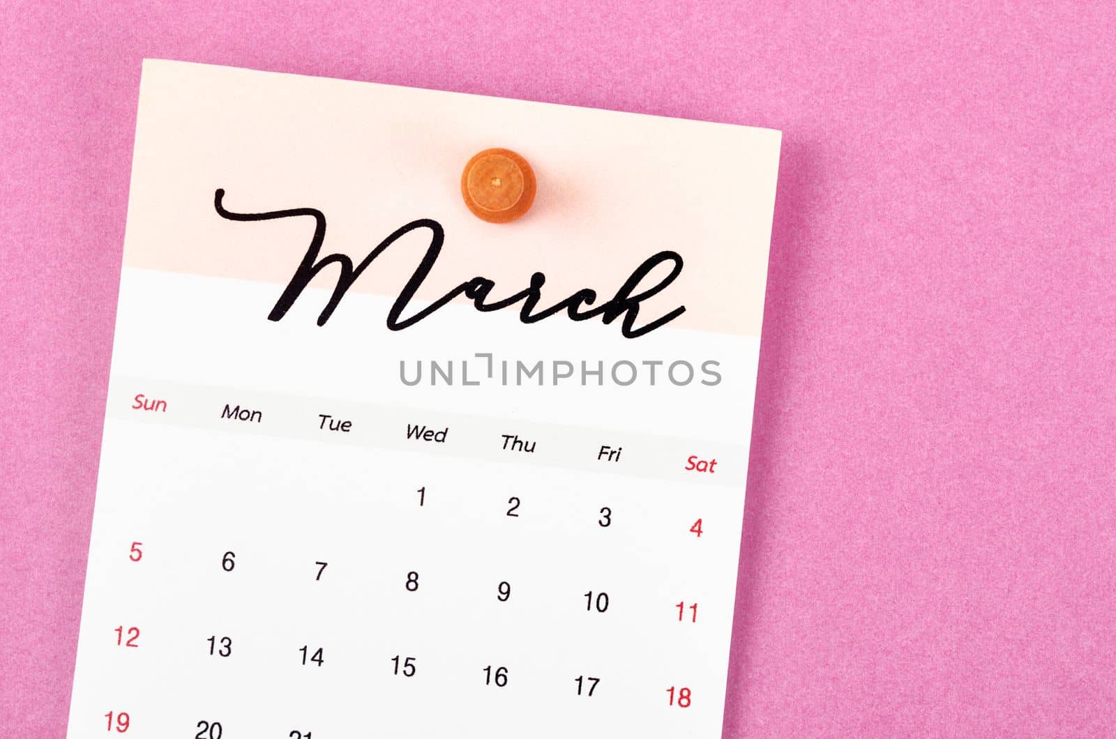 The March 2023 calendar and wooden push pin on pink colour background. by Gamjai