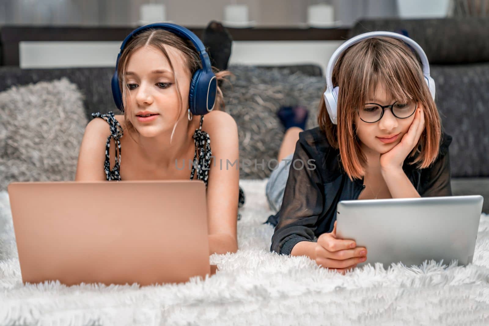 generation Z. adolescent children use modern technology at home and use headphones, laptops and tablets for entertainment and education by Edophoto