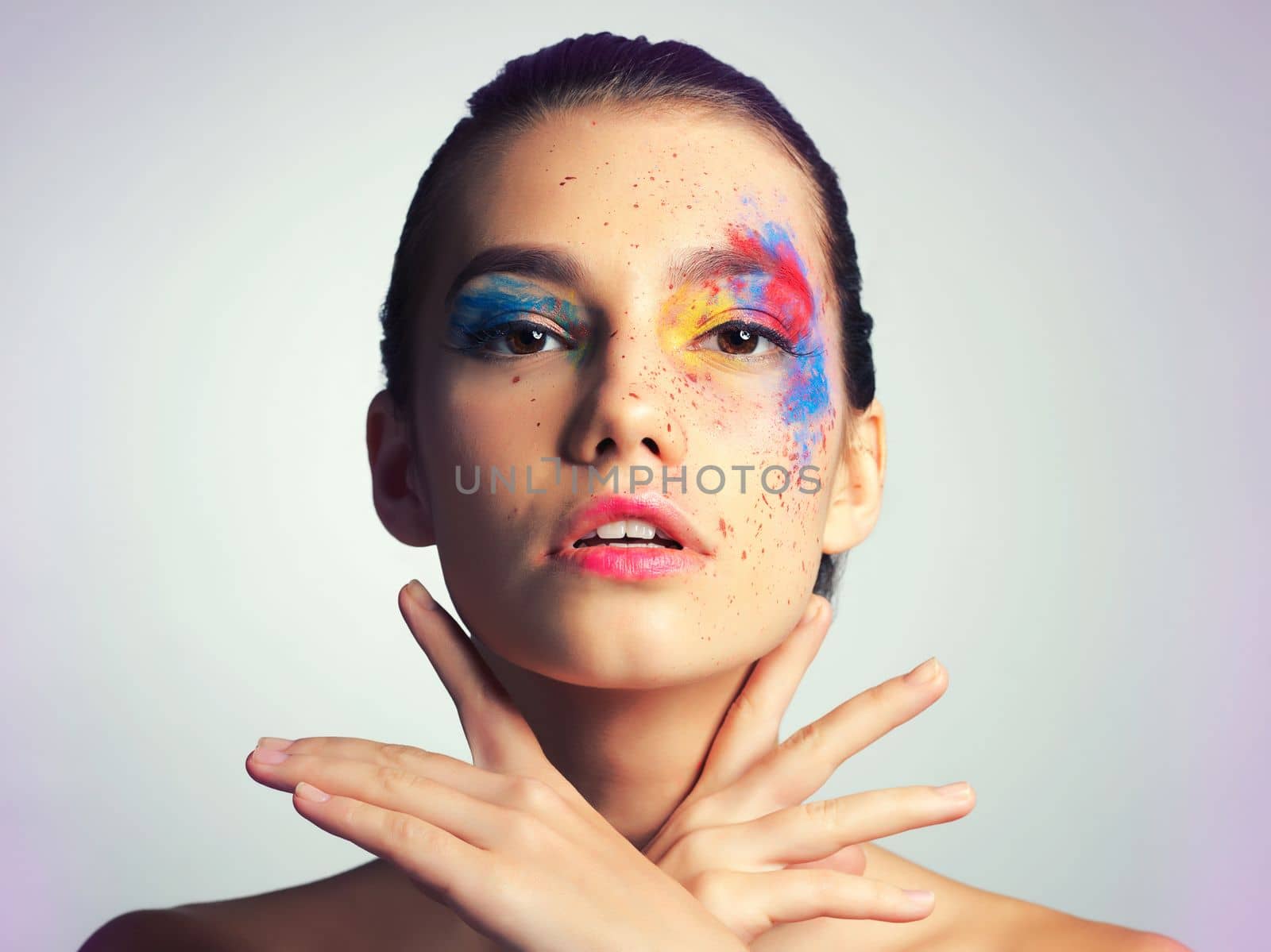 Art around her eyes. Studio shot of an attractive young woman posing with her face brightly painted