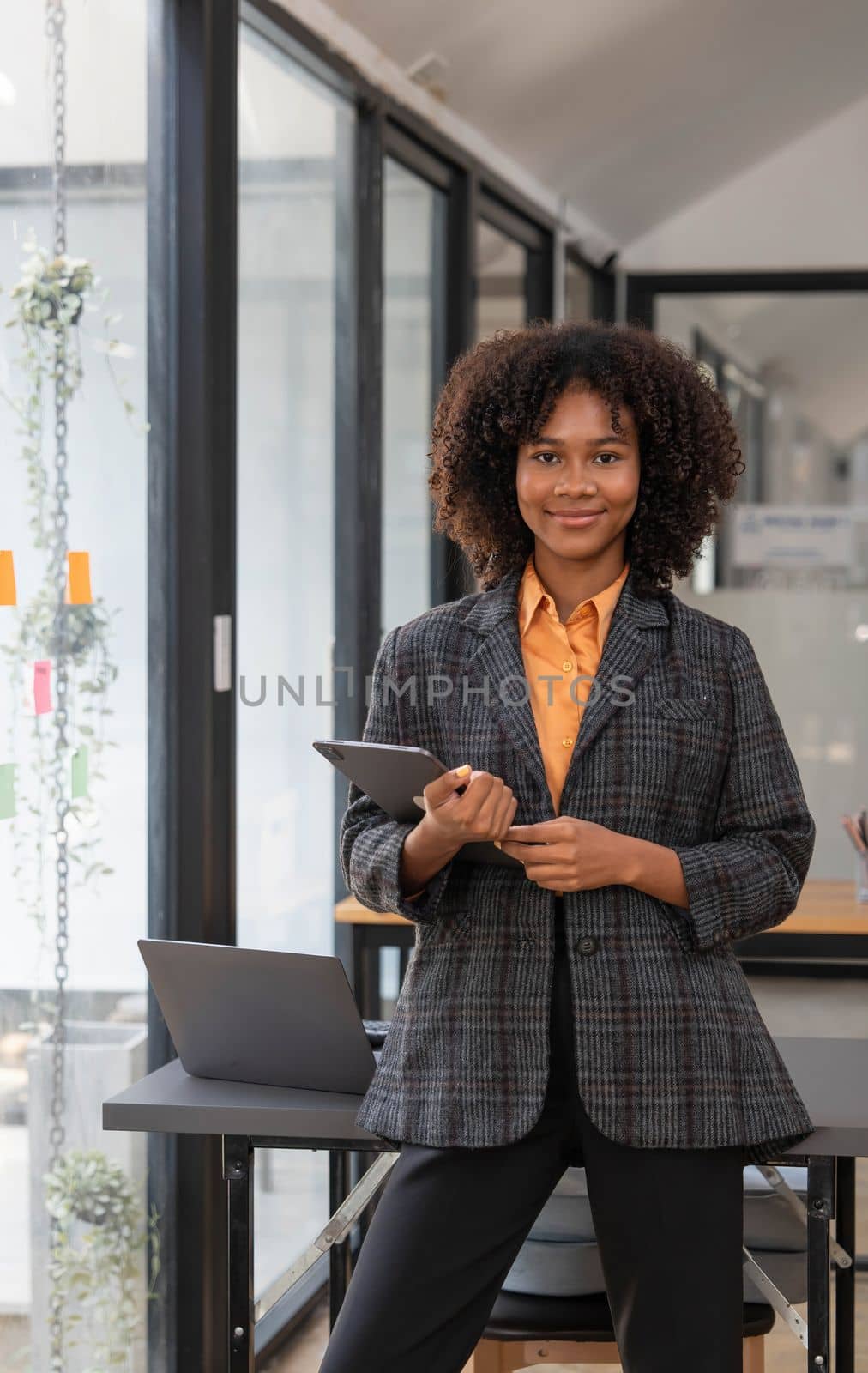 Attractive Asian businesswoman with smile standing with clipboard holding paperwork and taking note of work detail at office and looking at camera. by wichayada