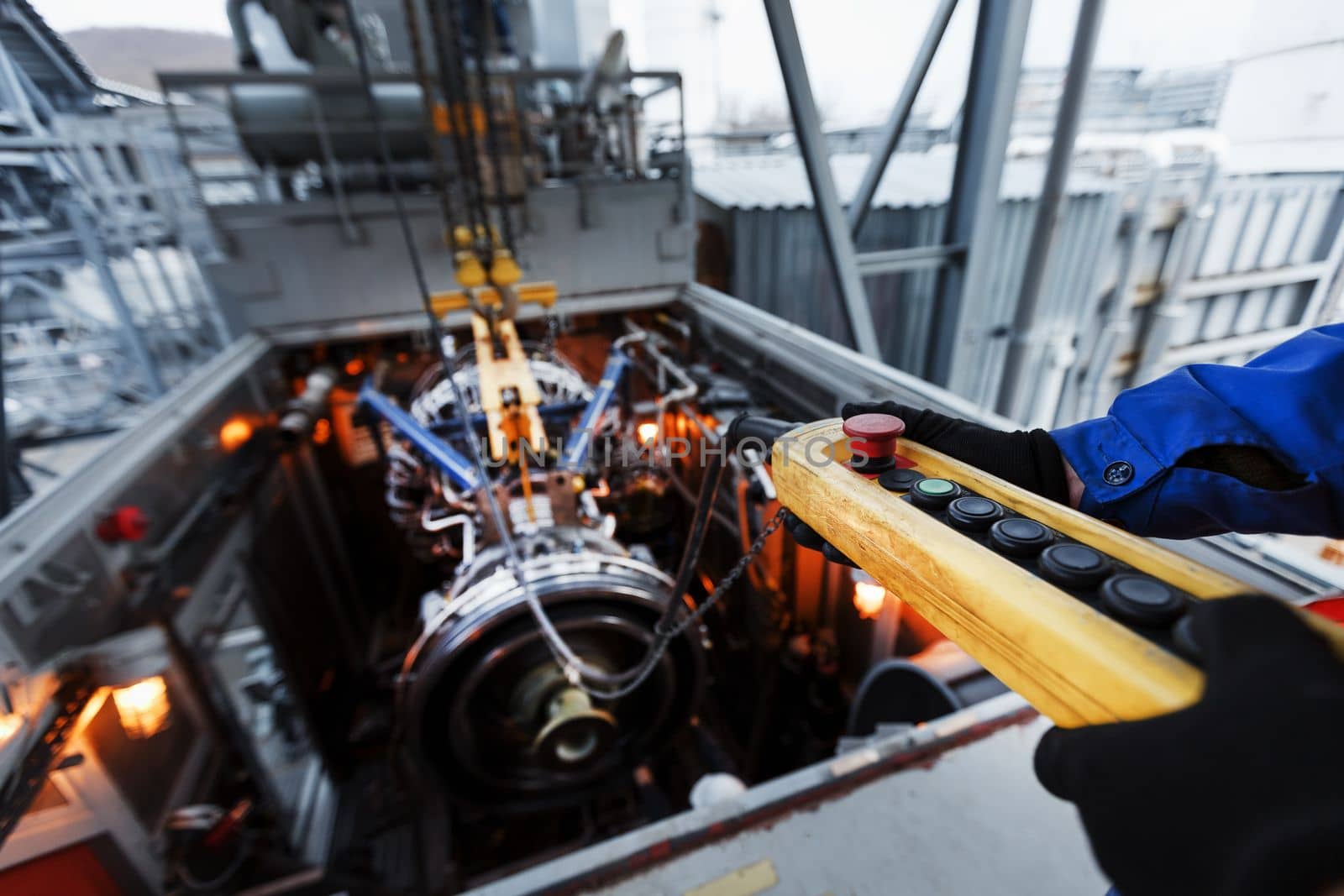 The engine of a gas turbine compressor hangs on a crane during installation in a module for generating electricity