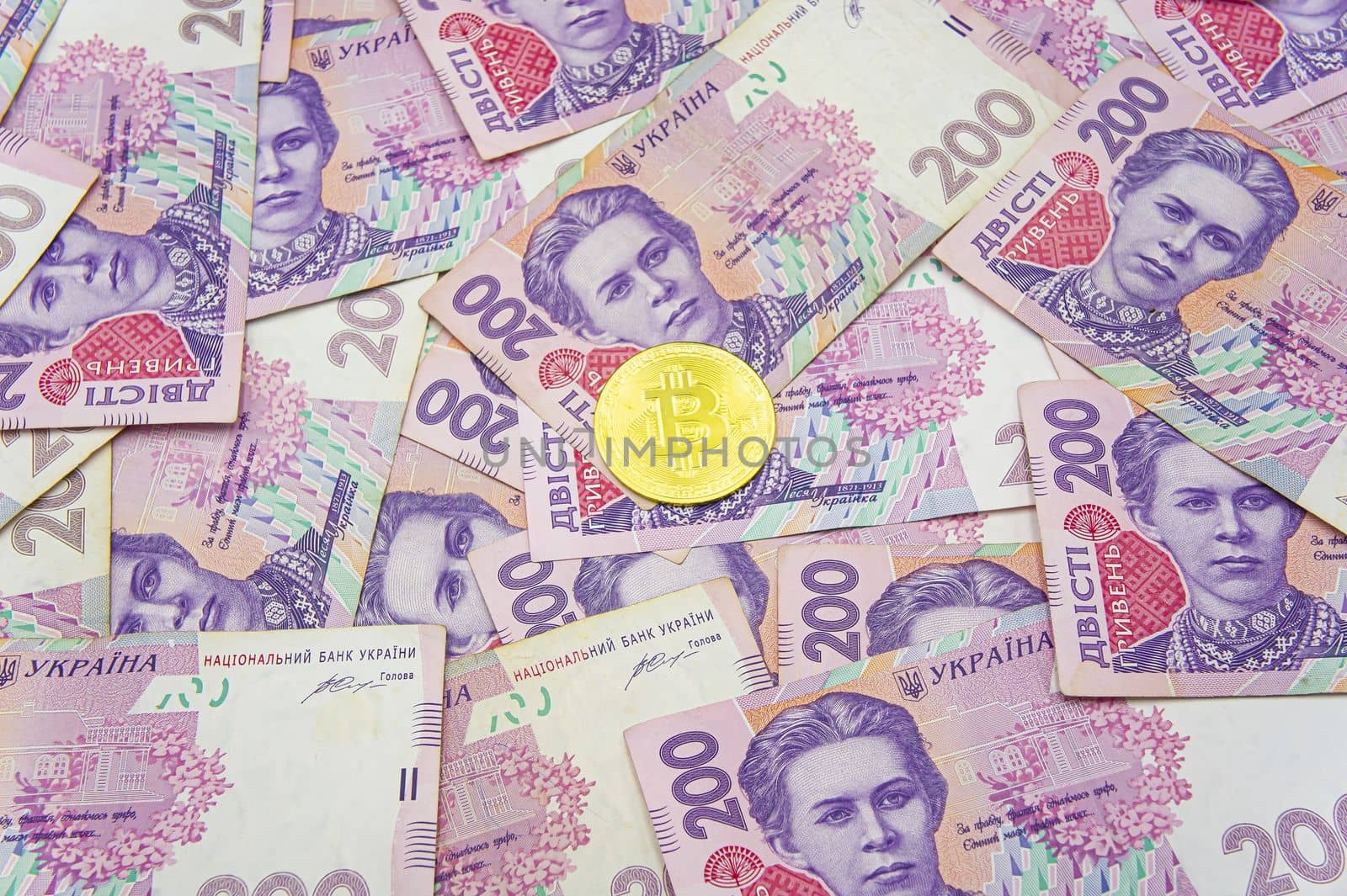 Golden bitcoin on two hundred ukrainian hryvnia bills background by mr-tigga