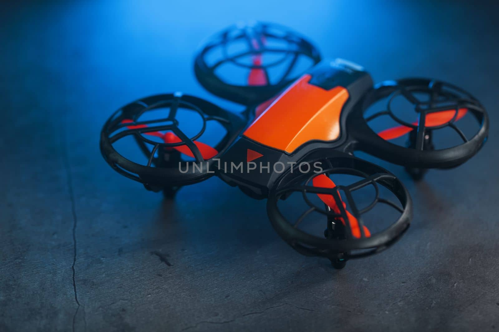 Orange quadcopter mini spy drone on a dark background with blue backlight and free space