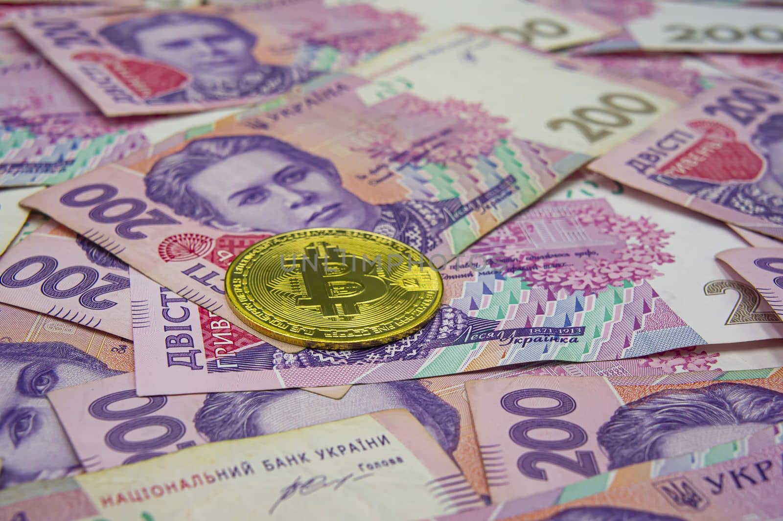 Golden bitcoin on two hundred ukrainian hryvnia bills background by mr-tigga