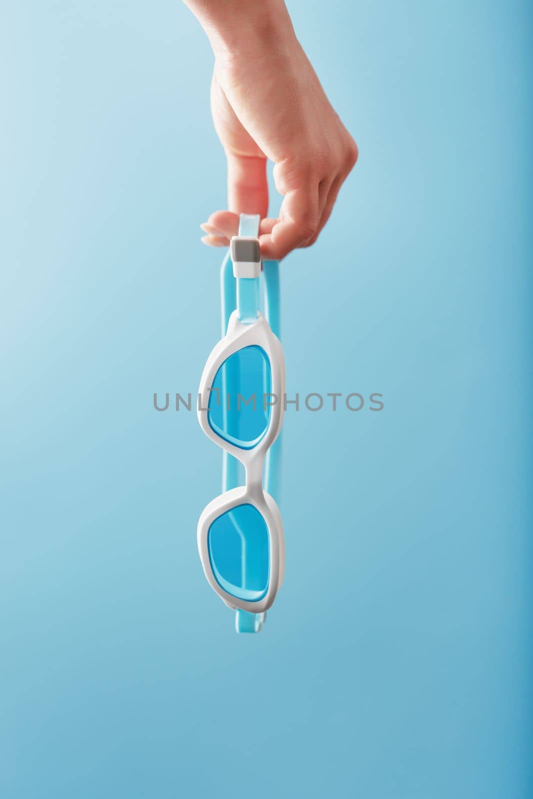 White swimming goggles on a blue background in a minimalist style with free space