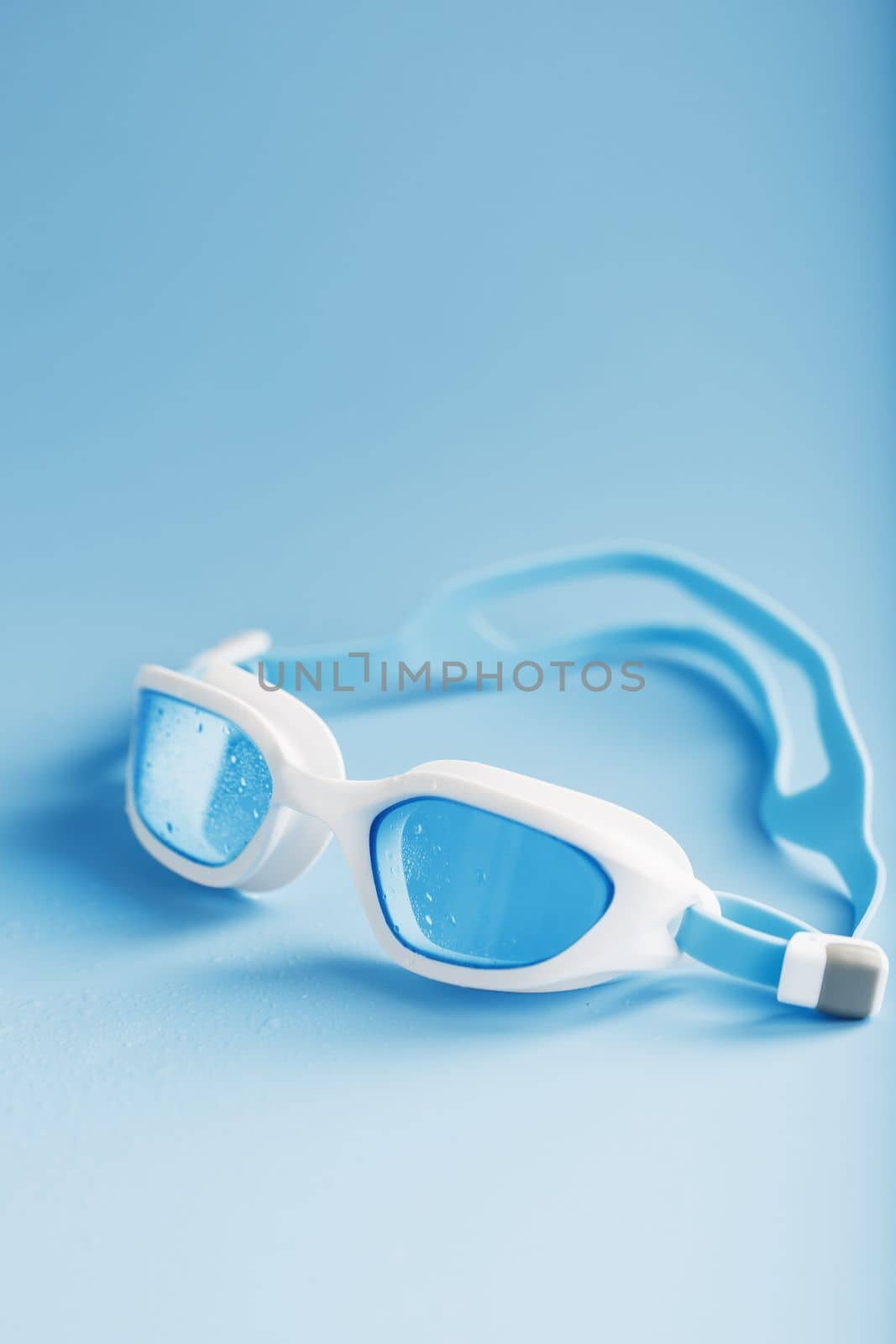 White swimming goggles on a blue background by AlexGrec