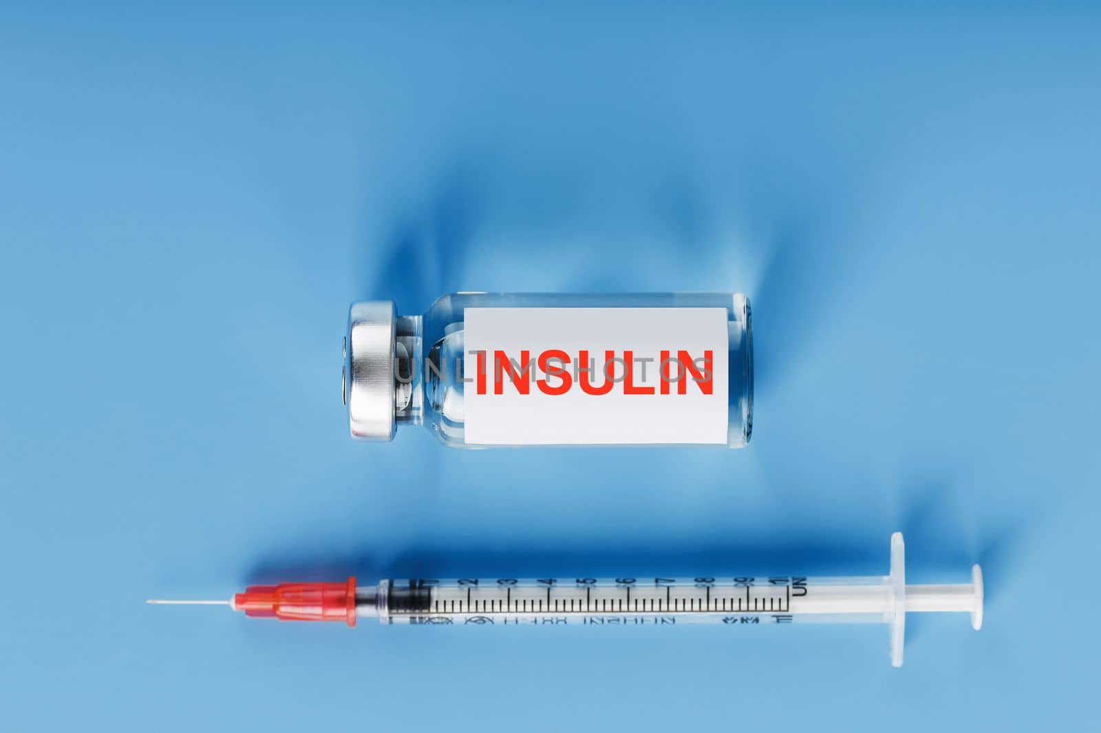 Ampoule bottle with insulin, needles and syringes for medical subcutaneous injection on a blue background