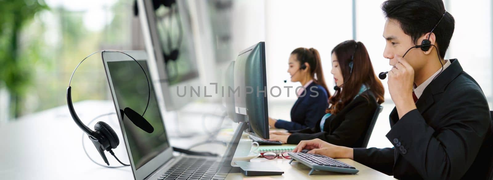 Business people wearing headset working in office in widen view to support remote customer or colleague. Call center, telemarketing, customer support agent provide service on telephone video call.