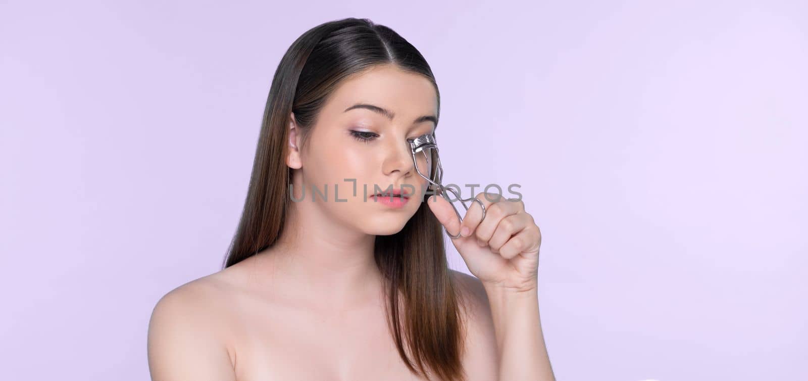 Closeup happy young charming brunette holding eyelash curler in her hand. by biancoblue