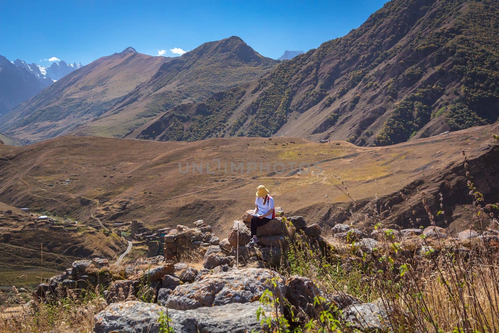 A tourist girl sits on a stone in the mountains and looks at the route map for further travel