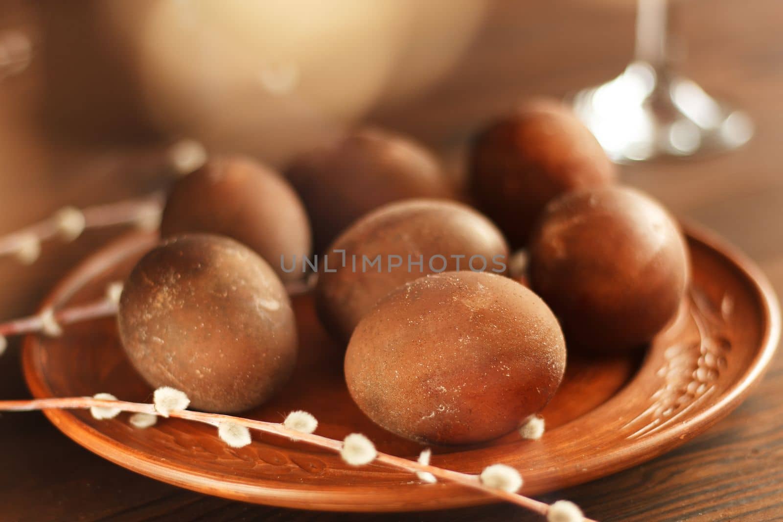 painted eggs on a plate with a sprig of willow on a wooden table. Easter celebration. by lara29