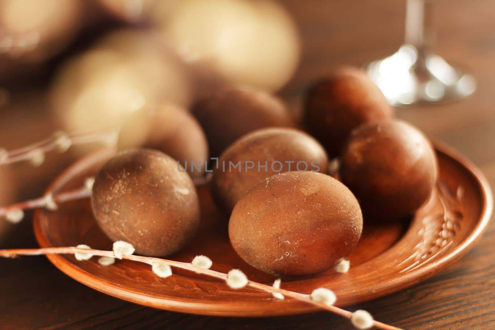 painted eggs on a plate with a sprig of willow on a wooden table. Easter celebration.