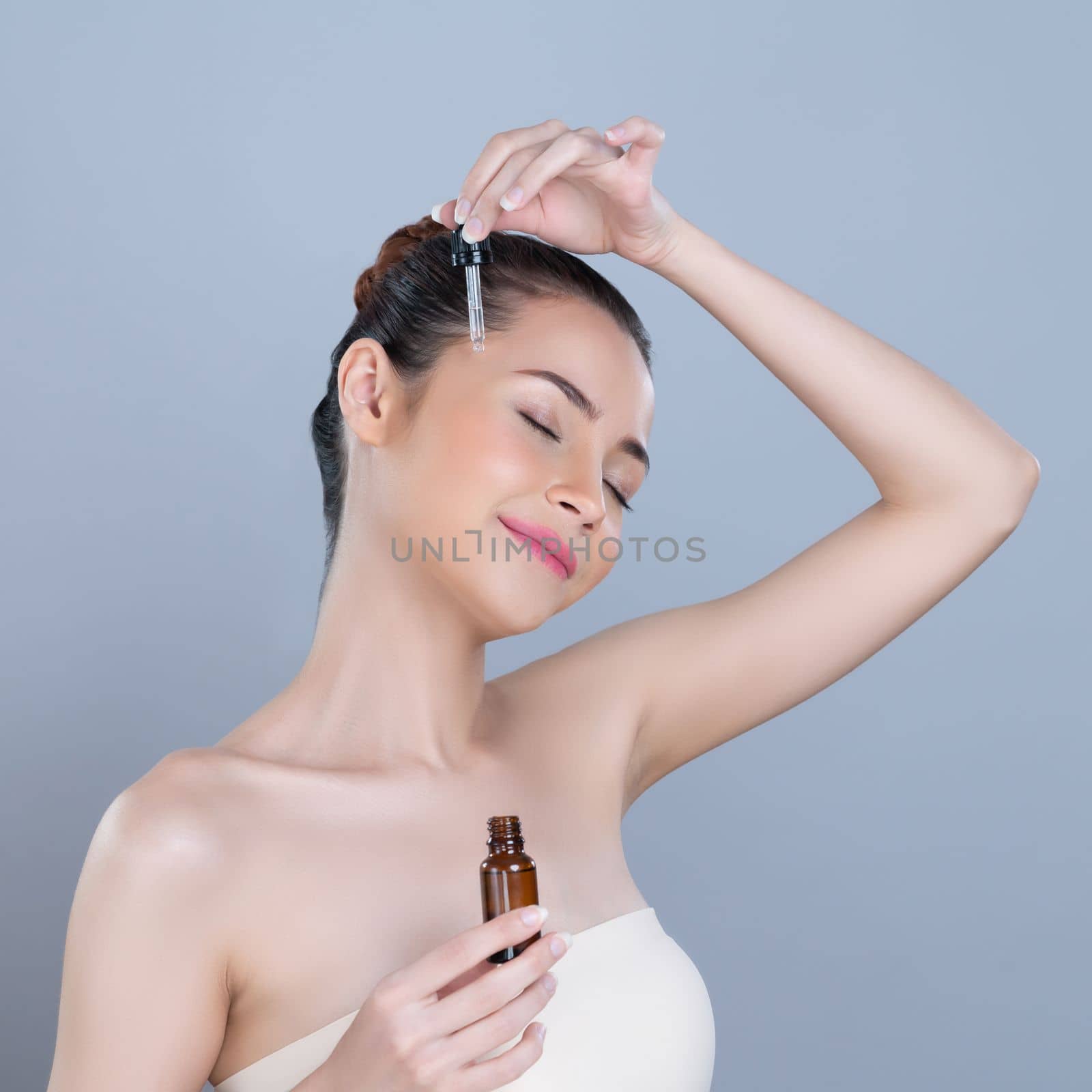 Glamorous portrait of beautiful woman applying extracted cannabis oil bottle for skincare product. CBD oil dropper pipette for cosmetology treatment and cannabinoids concept in isolated background.