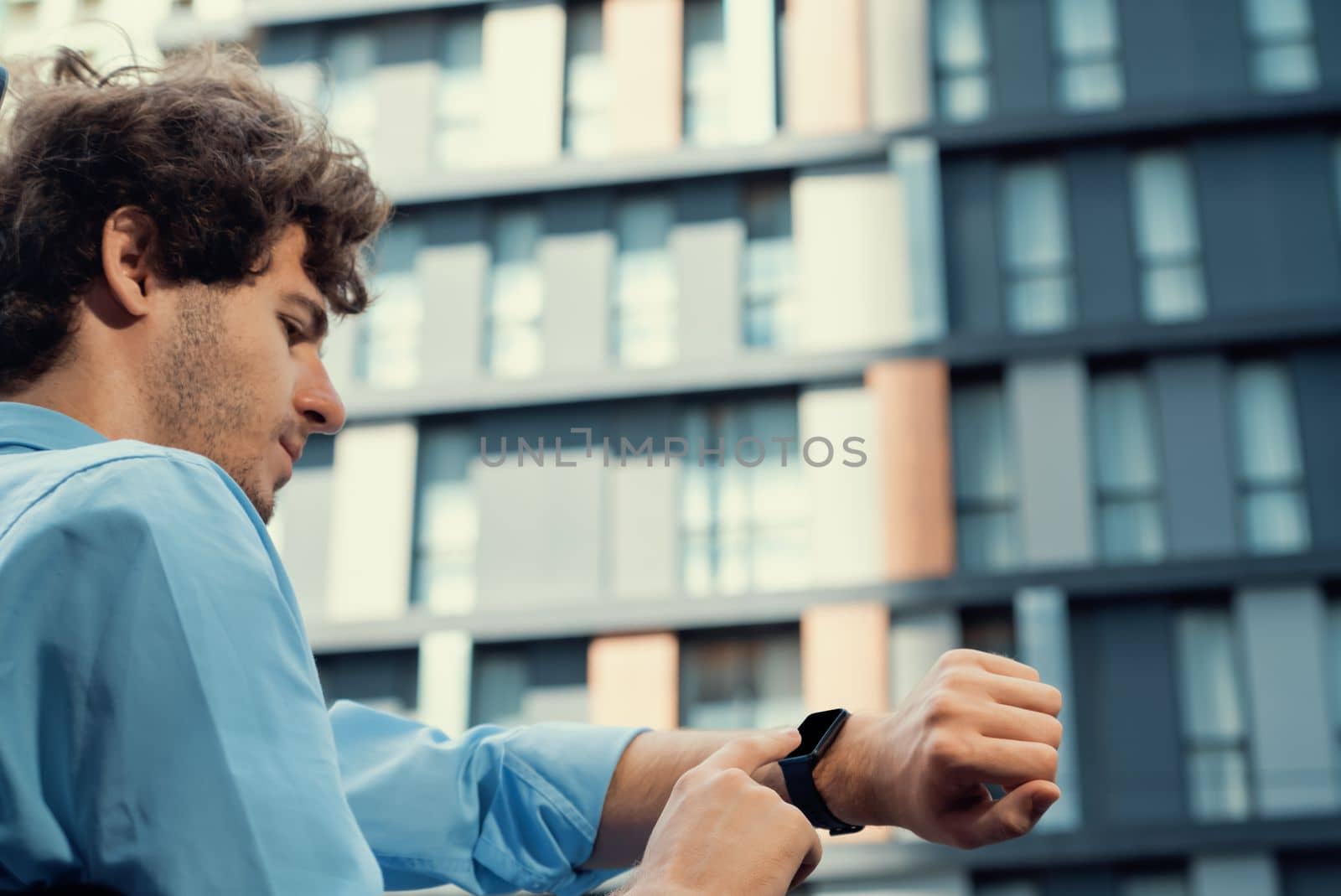 Young progressive businessman using touchscreen smartwatch to check time. by biancoblue