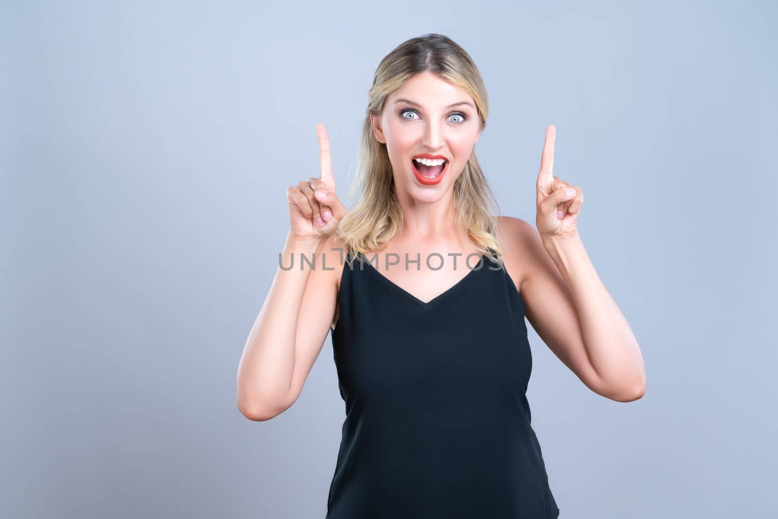 Alluring portrait of beautiful woman with perfect makeup clean skin pointing finger up in copyspace isolated background. Promotion indicated by hand gesture concept for skincare advertisement.