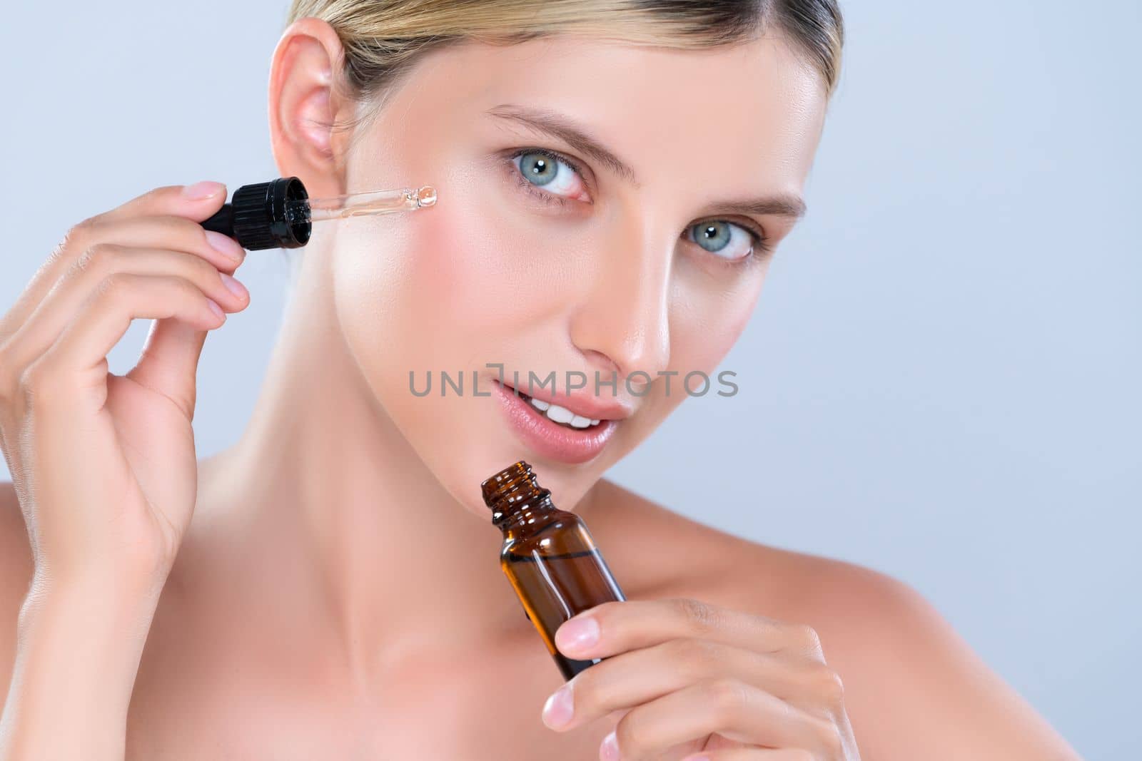 Closeup alluring portrait of beautiful woman in isolated applying extracted cannabis oil bottle for skincare product to her face. Cannabis and CBD oil for facial treatment cosmetology beauty concept.