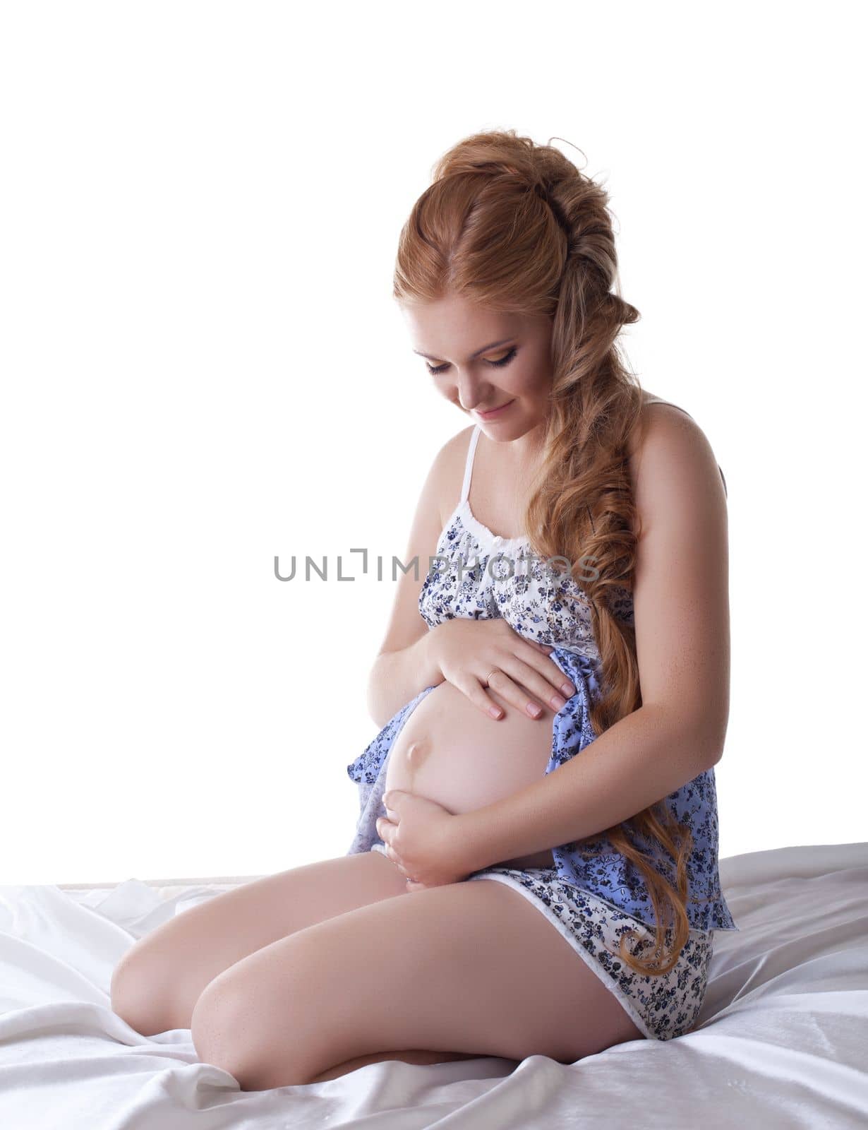 Beautiful pregnant woman sit in silk bed isolated