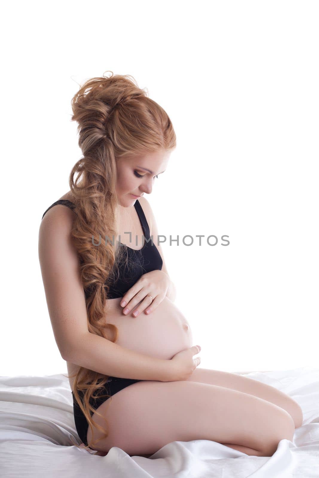 young pregnant woman sit in black lingerie in silk bed