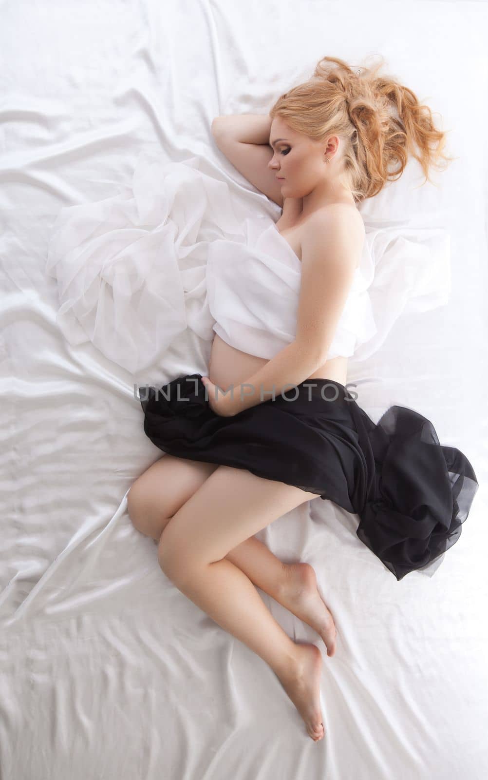pretty pregnant woman with long hairs sleeping under black and white silk
