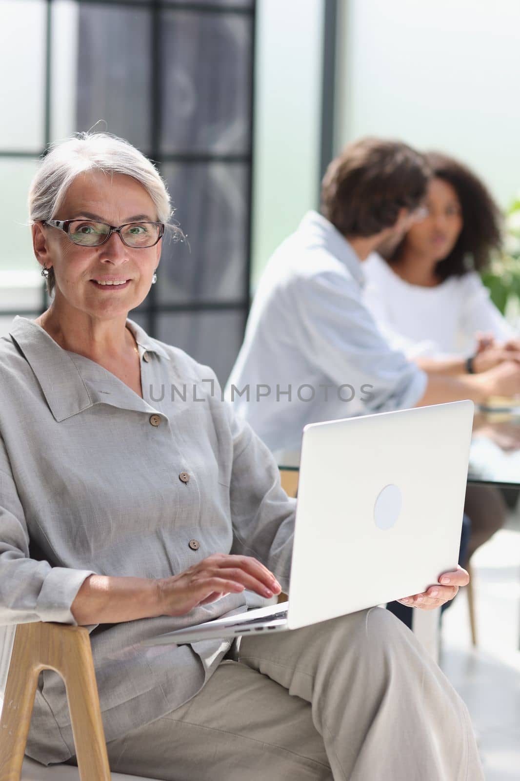 mature woman sitting with laptop looking at camera.