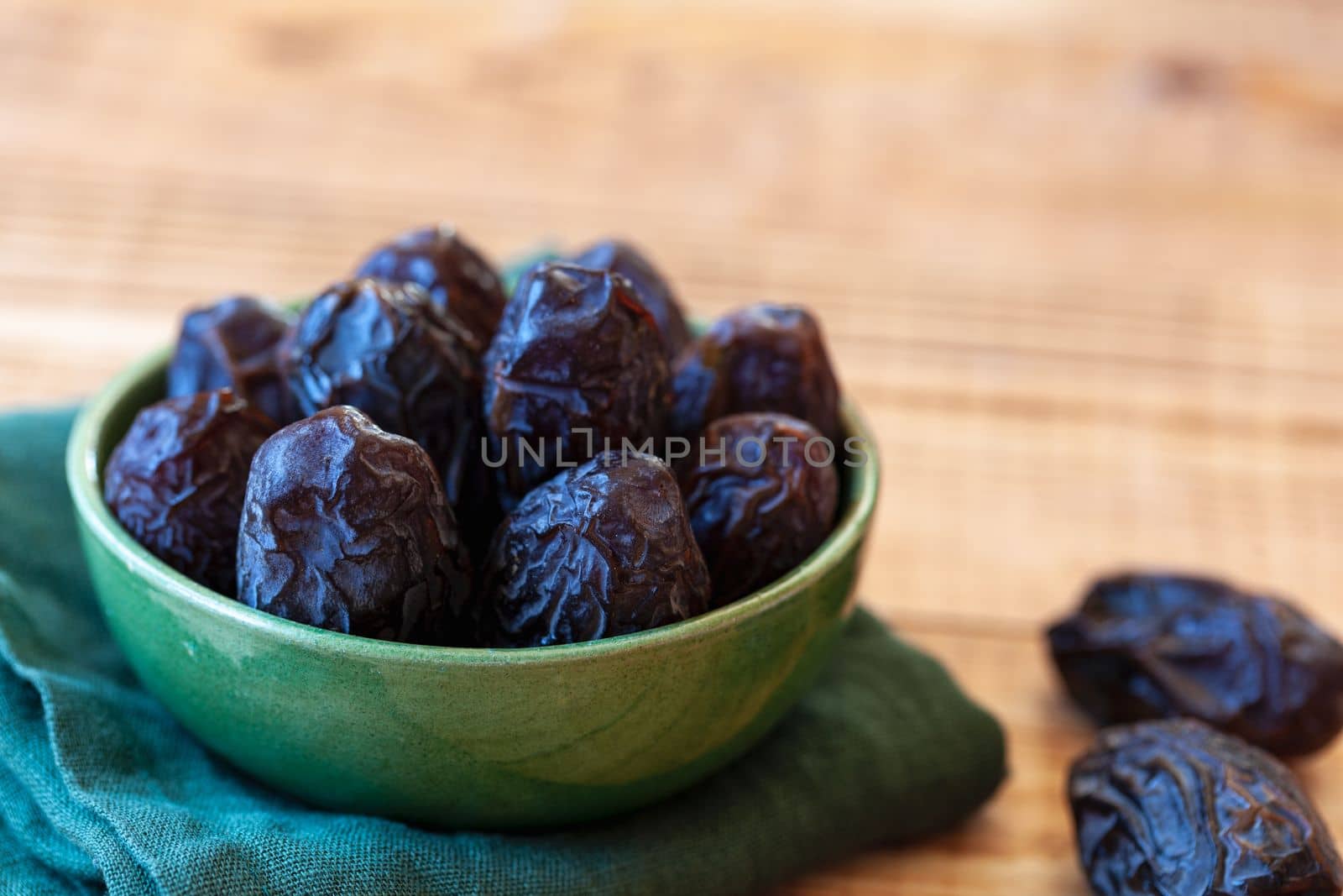 bowl of date fruits on a wooden table, side view