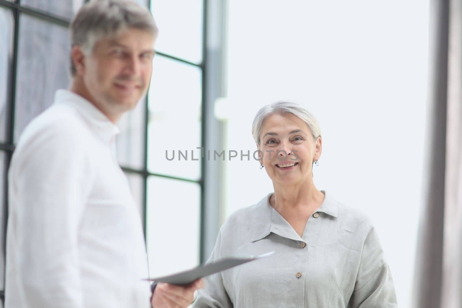 Professional business man and woman standing back to back in the office looking at the camer