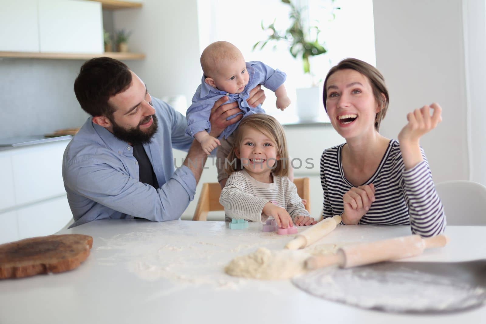 Happy parents playing with their children in the kitchen