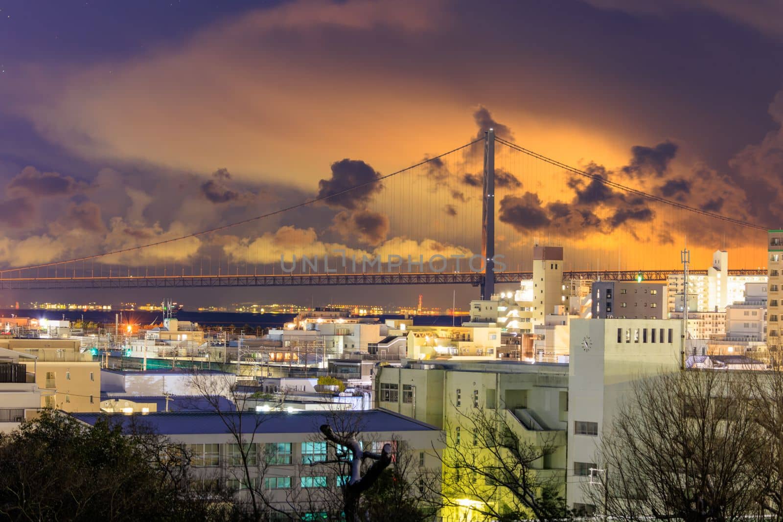 Glow from city in low clouds over Akashi Bridge and city at night. High quality photo