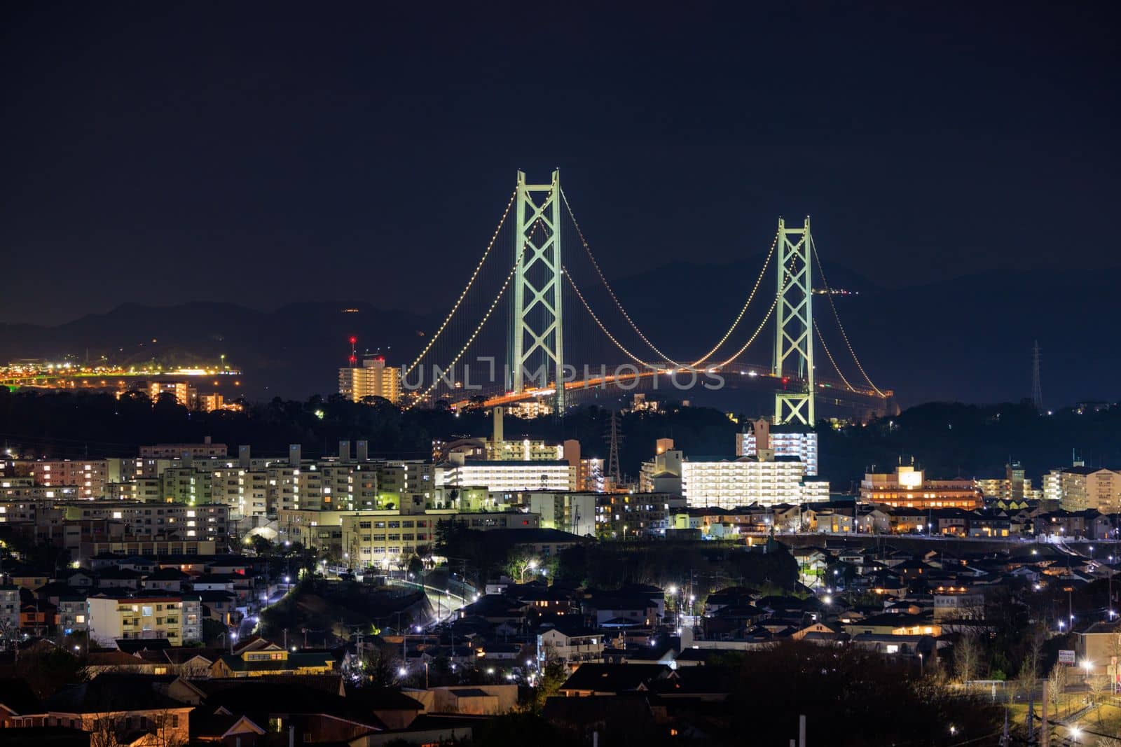 Akashi Kaikyo Suspension Bridge and Apartment Buildings Lit at Night. High quality photo