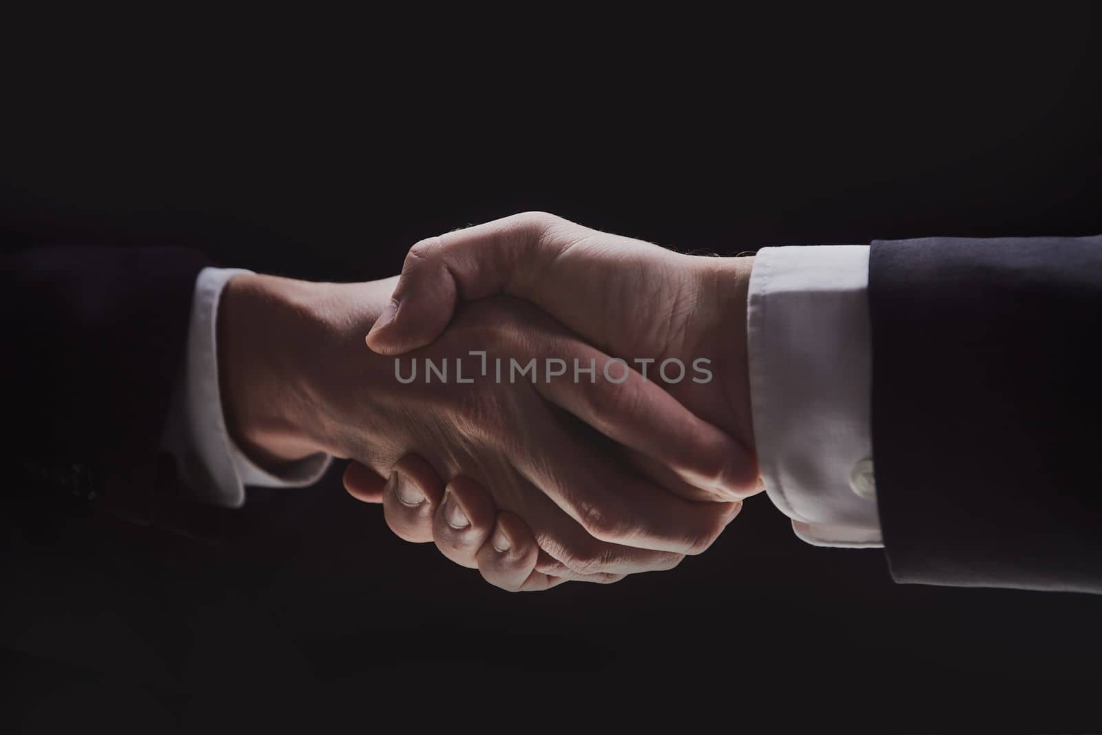Photo of two men in suits shaking hands on a black background by Prosto