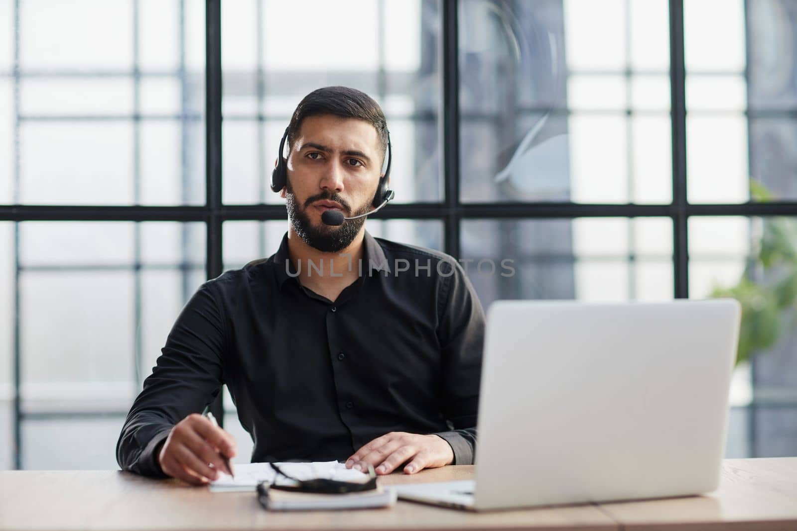 Young handsome male customer support phone operator with headset working in call center.