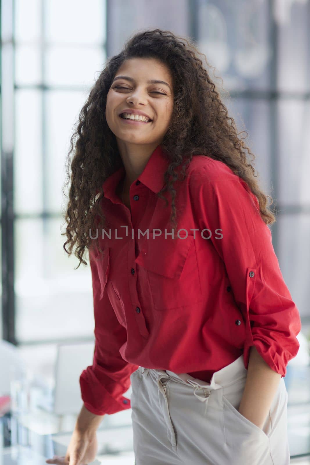 Image of young beautiful joyful woman smiling while working with laptop in office