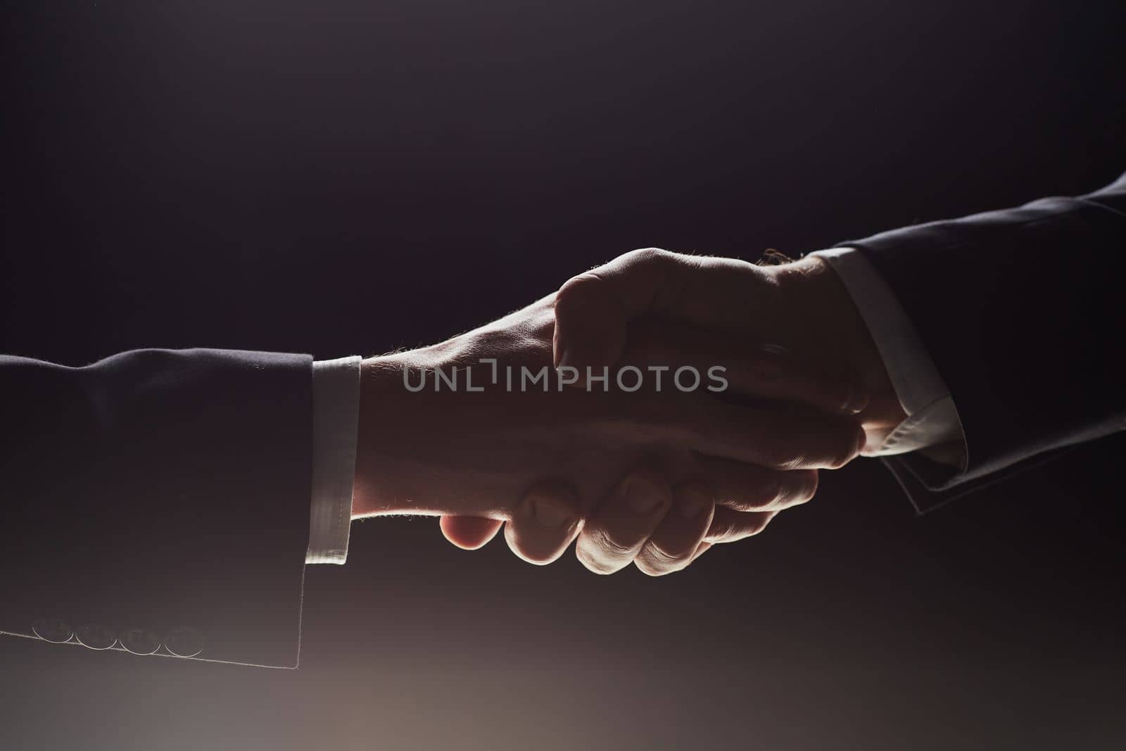 Photo of two men shaking hands on a black background