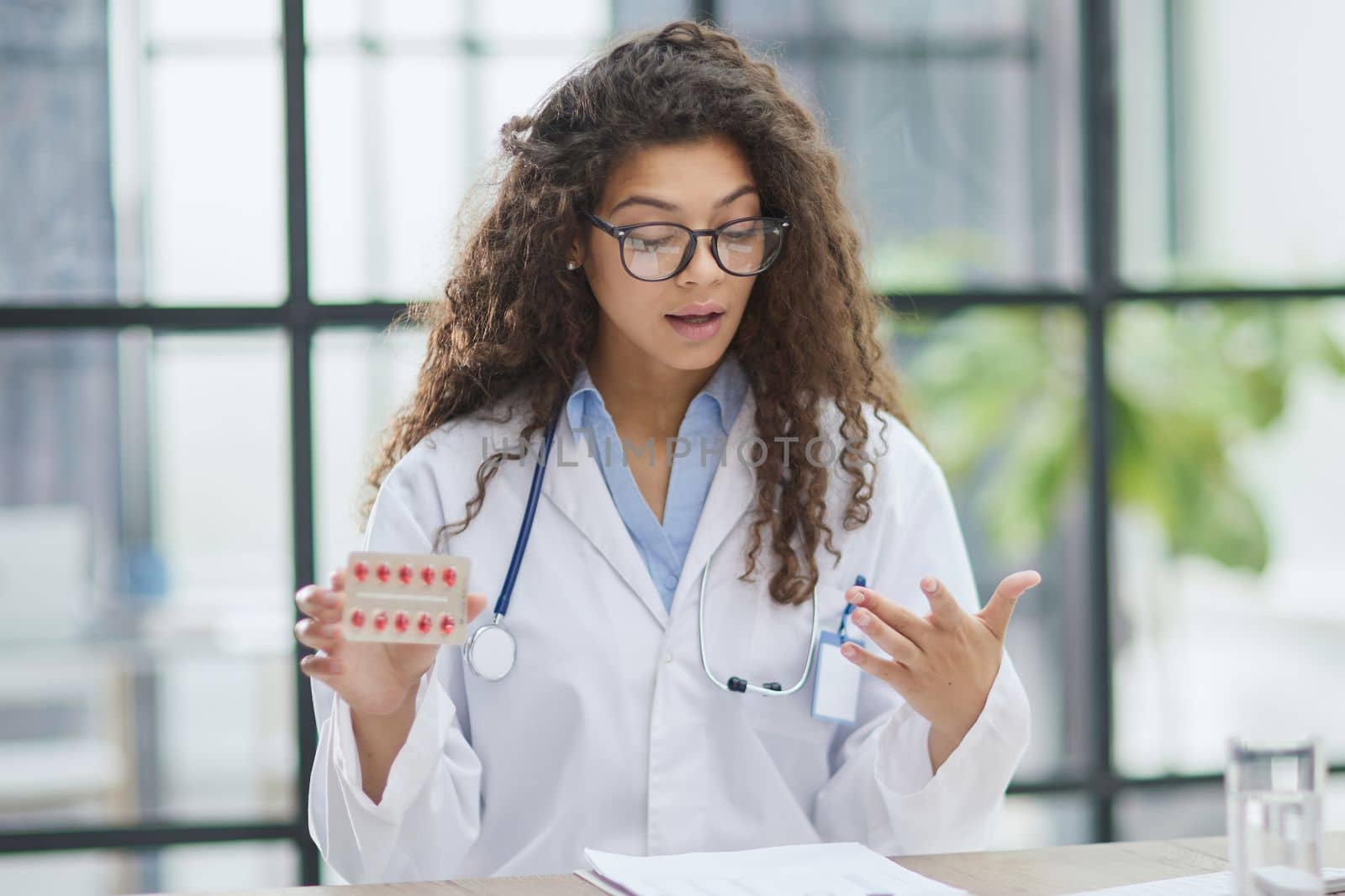 Portrait of young female doctor in white coat at workplace