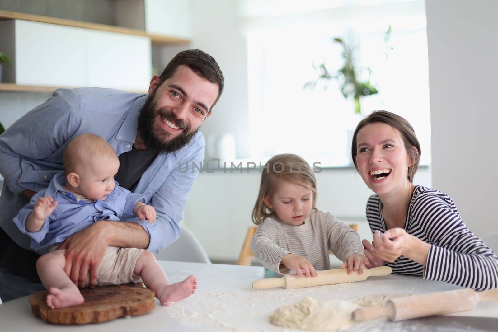 Happy parents playing with their children in the kitchen