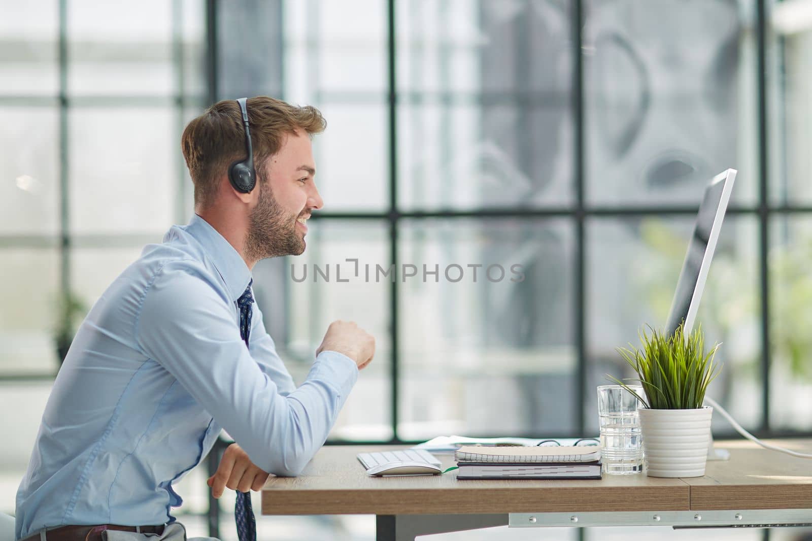 Young handsome male customer support phone operator with headset working in his office